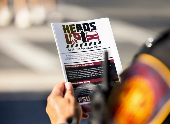 police officer holding heads up flyer