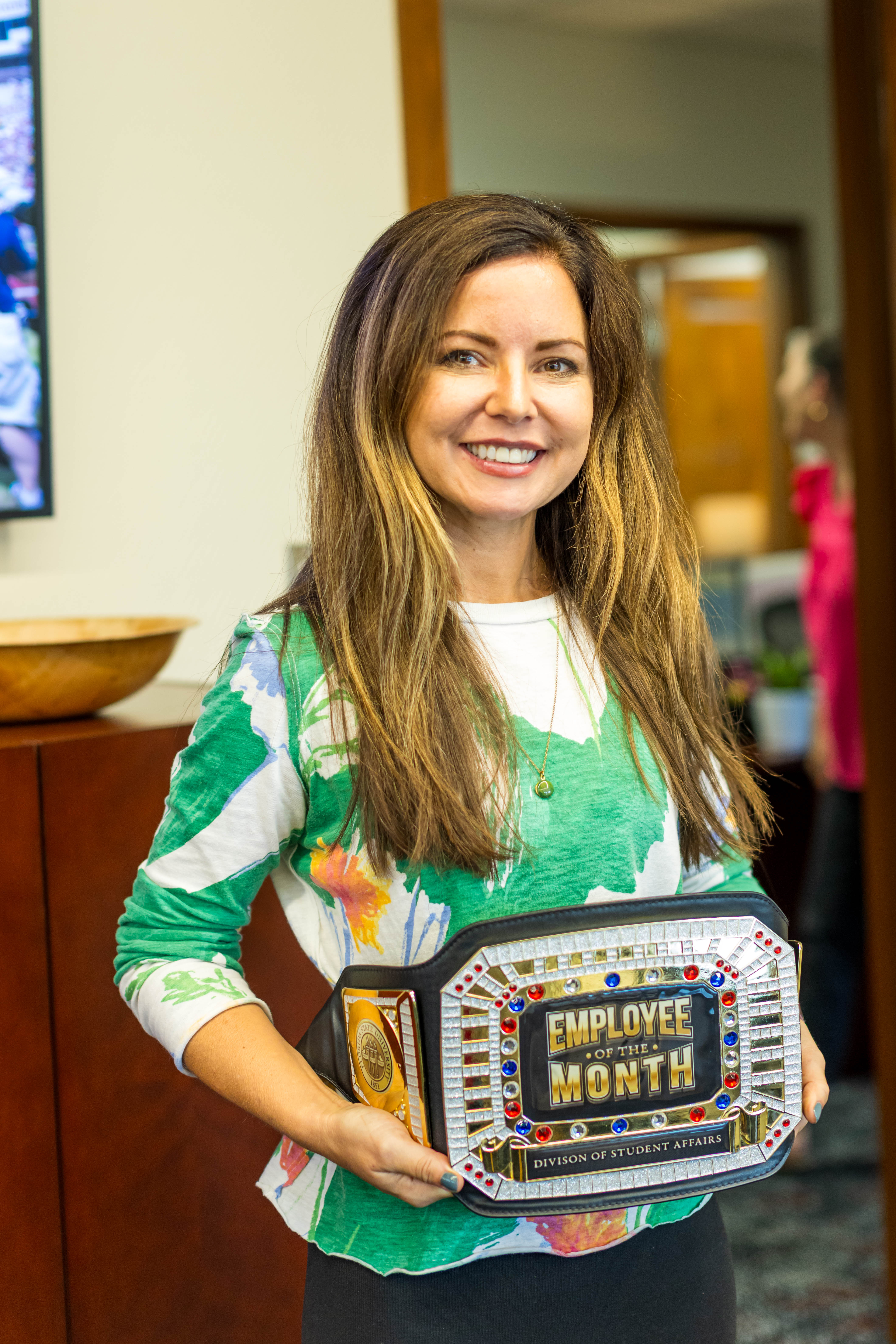 Katie Townsend holding the Employee of the Month heavyweight belt