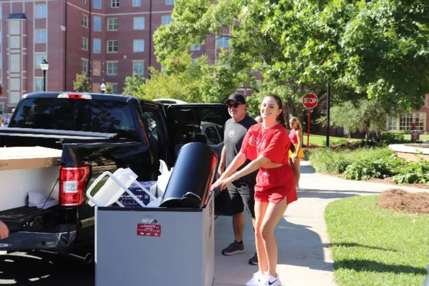 student rolling a cart full of dorm items 