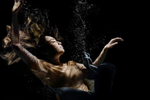 woman with eyes closed suspended in water on a dark background
