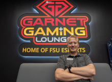 Matthew Nelson standing in front of Garnet Gaming Lounge sign
