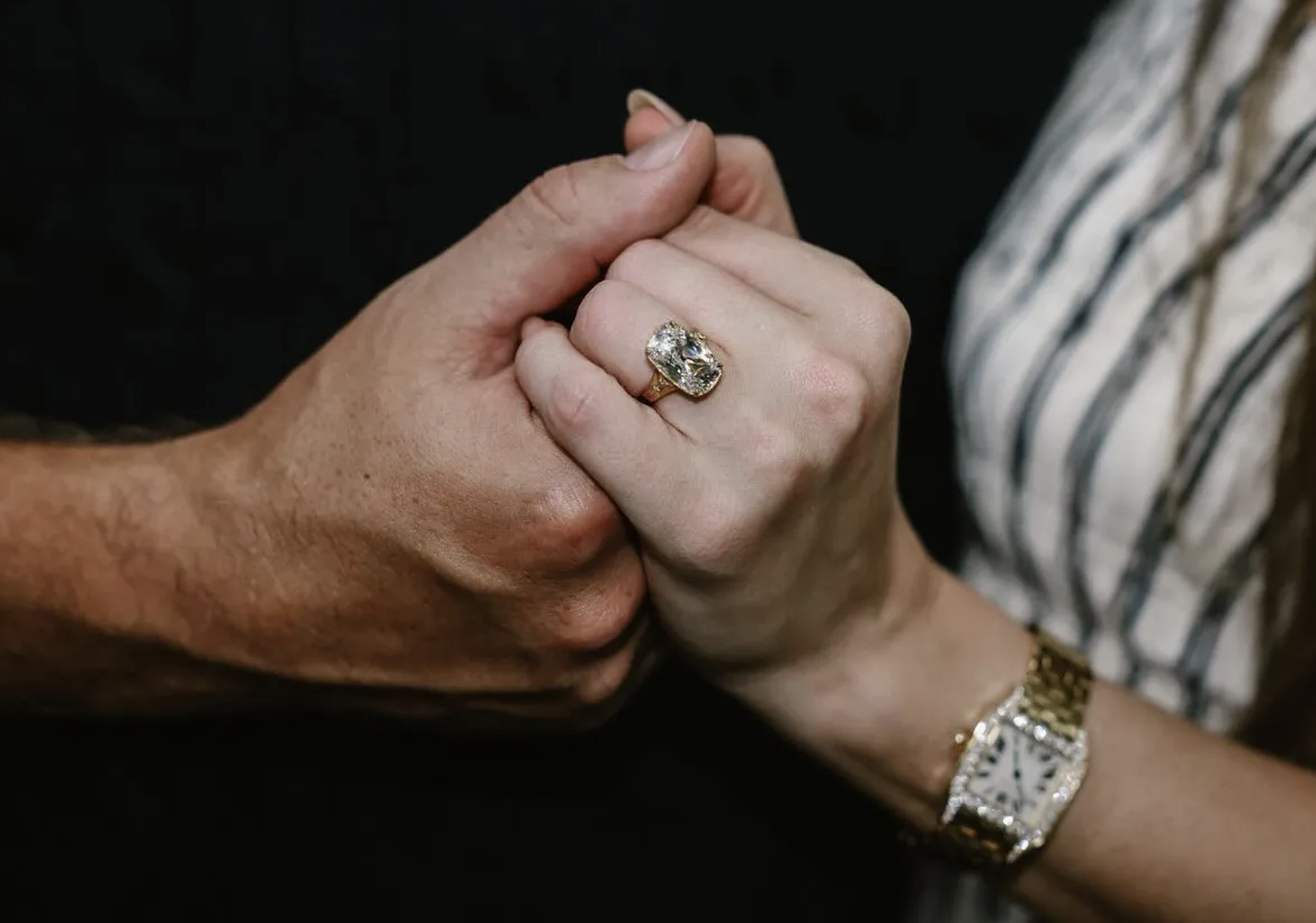 two hands being held together, one hand with a large engagement ring designed by Kindred Lubex