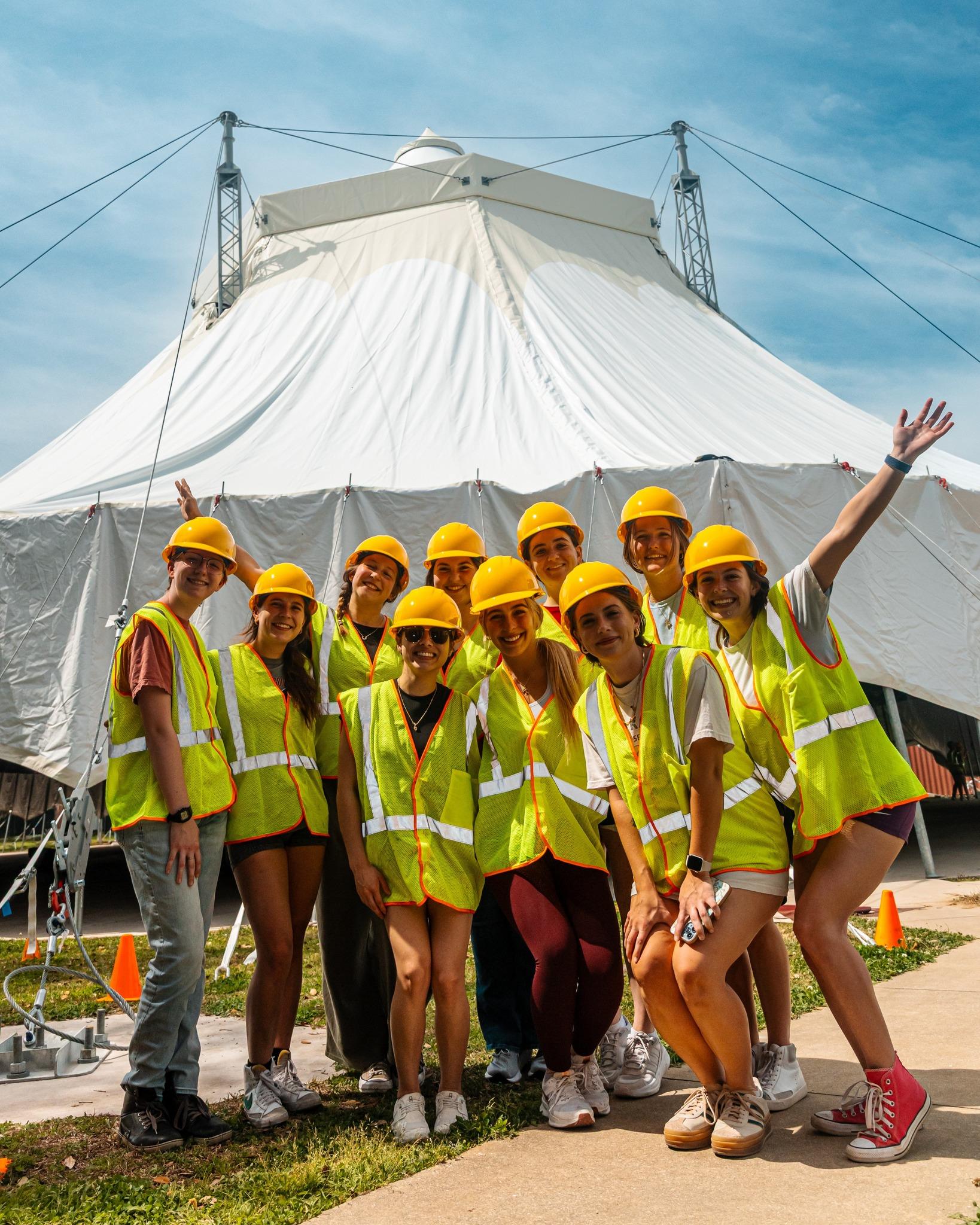 Students in high-vis gear stanfing in front of a newly-raised circus tent