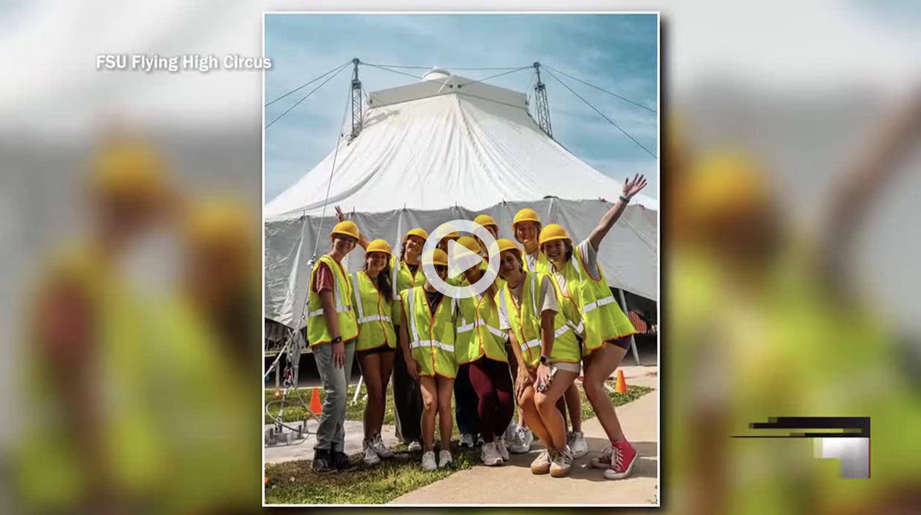 students standing in high-vis construction gear with the circus big top tent behind them with an overlaid youtube play button